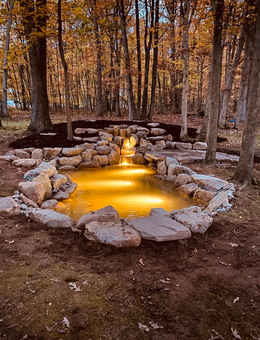 Amber-lit woodland pond and stream at dusk under an autumn canopy, built by Aquastyle Creations